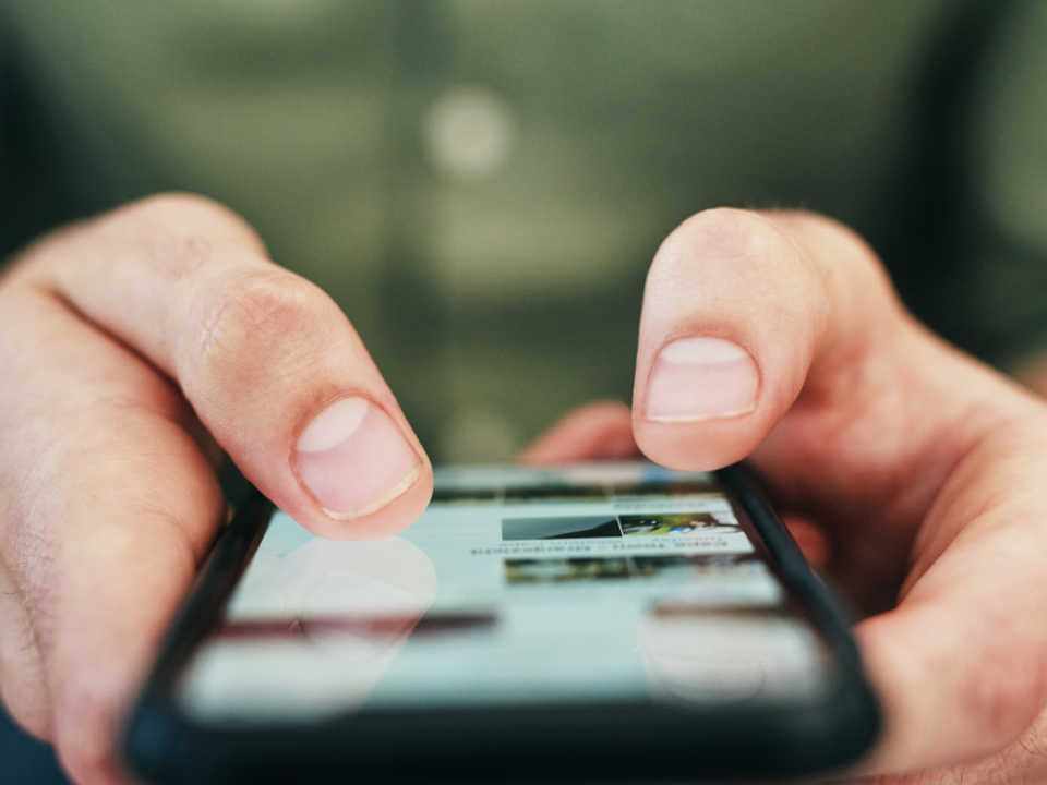 A photo of someone holding a cell phone and posting something online.